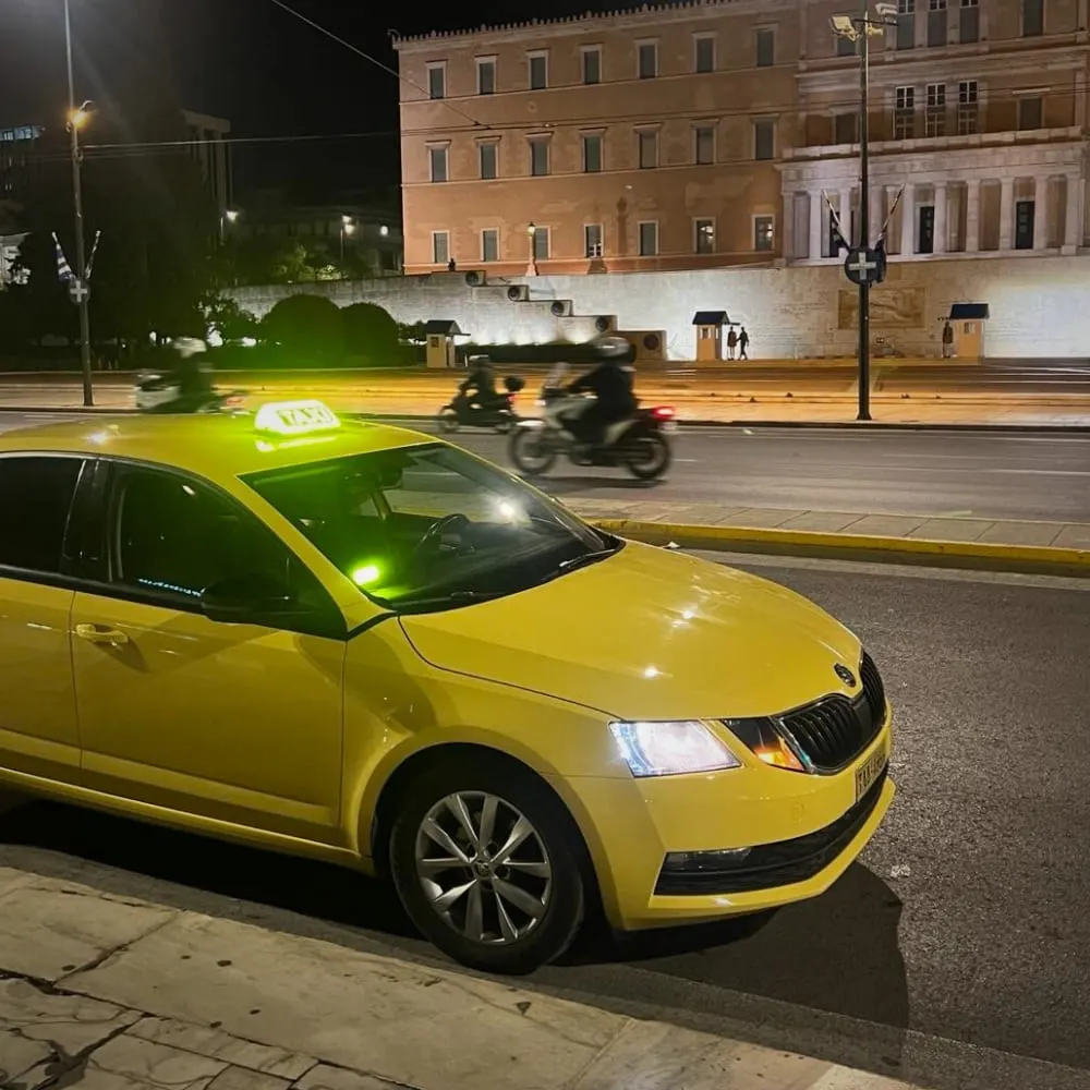 Yellow taxi at night in front of the Greek Parliament